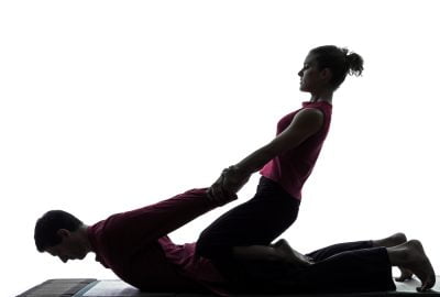 Girl stretching arms of man during sports massage session