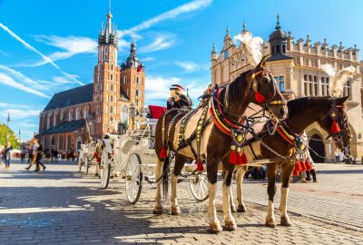 Krakow city guide.Rynek Glowny.01 Carriage with horses to the background of the Saint Mary's Basilica and City Hall on the central market square Rynek Główny in Kraków