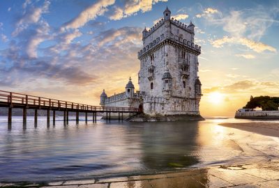 Lisbon city guide.Belem Tower.01 Belém Tower ((Torre de Belém) at the Tagus River against the sunset sky in Lisbon