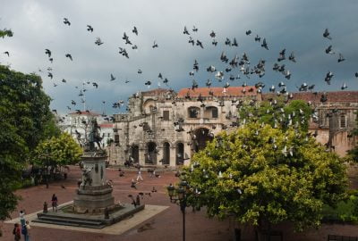 Santo Domingo city guide.Parque Colon with Cathedral and Columbus statue.01 Parque Colon in Santo Domingo with Cathedral and Columbus statue visited by flock of pingeons