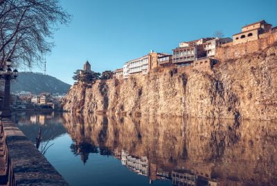 Tbilisi city guide.Metekhi church and houses over river Kura.02 Metekhi church and typical Georgian style houses located on the edge of a cliff above the river Kura in Tbilisi