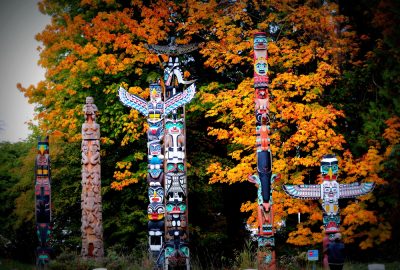 Vancouver city guide.Totem poles Stanley Park.02 Totem poles in in autumn foliage of Stanley Park in Vancouver