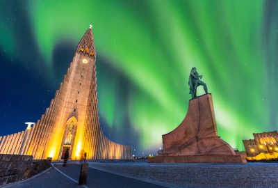 Reykjavik city guide.Hallgrimskirkja Cathedral and Northern Lights.01 Hallgrimskirkja Cathedral and statue of Leifur Eiríksson in Reykjavik to the backdrop of the Northern Lights