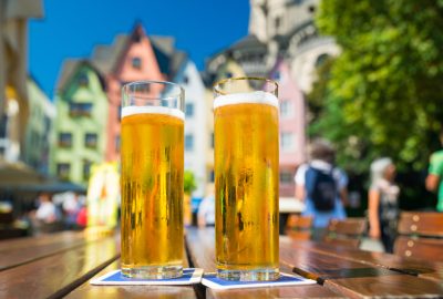 Cologne city guide.Kölsch beer.02 Two glasses of Kölsch beer to the backgdrop of Cologne's Old Town (Altstadt)